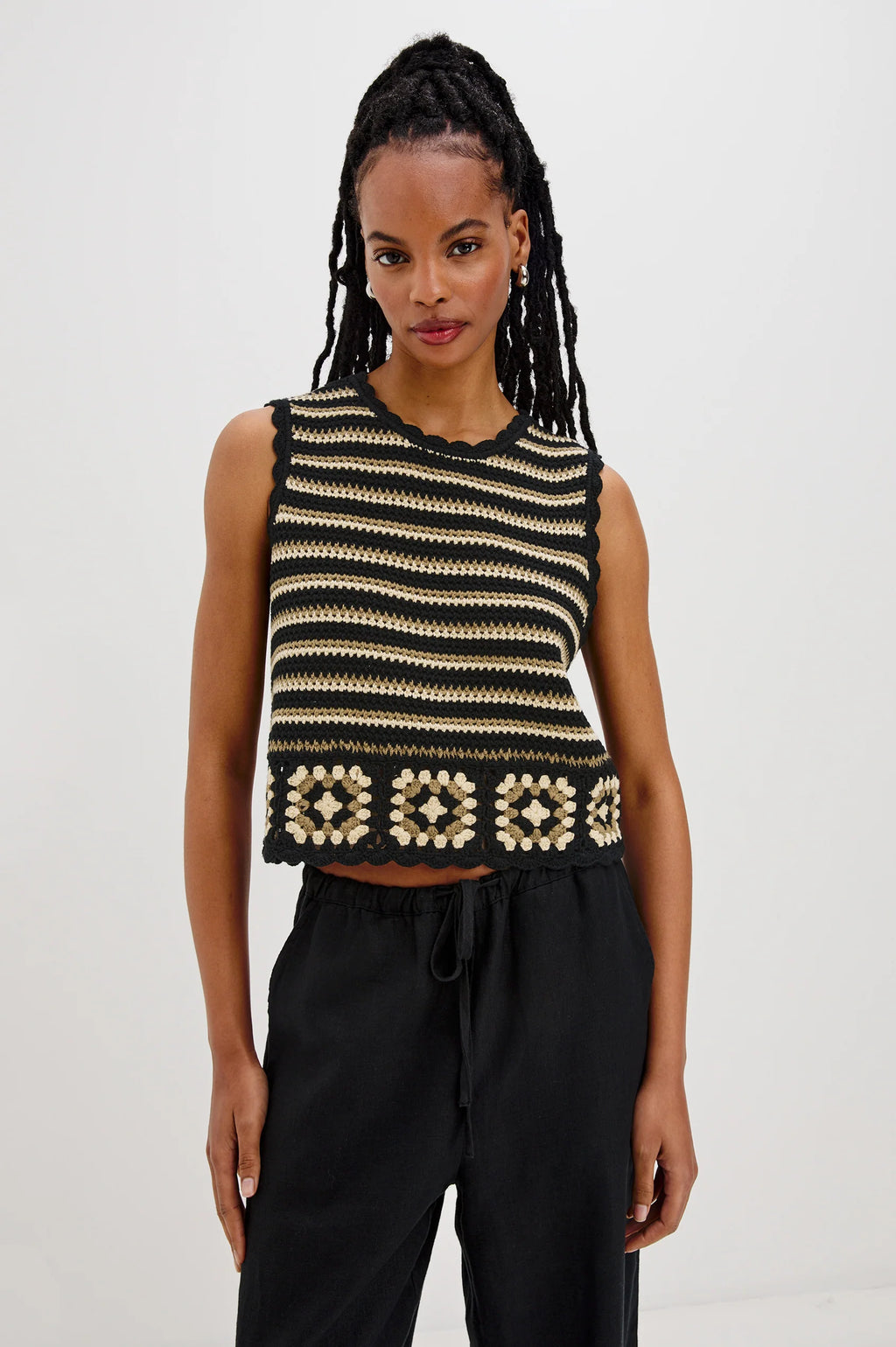 The Hazel is a cotton crochet tank with a cropped fit. Scallop detailing follows the neckline and arms, and a hand-crocheted panel lines the hem.