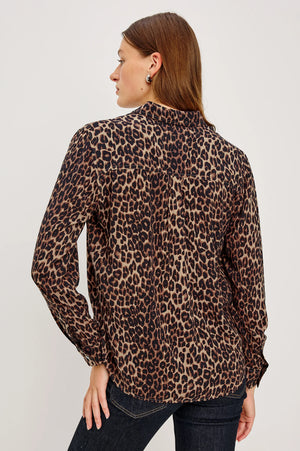 Woman wearing a leopard print blouse against a plain background