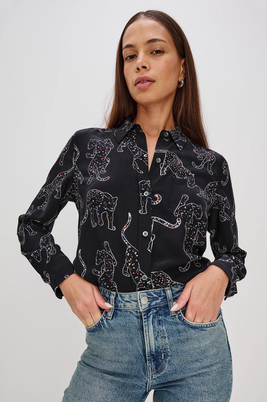 Woman wearing a black patterned shirt and blue jeans on a white background