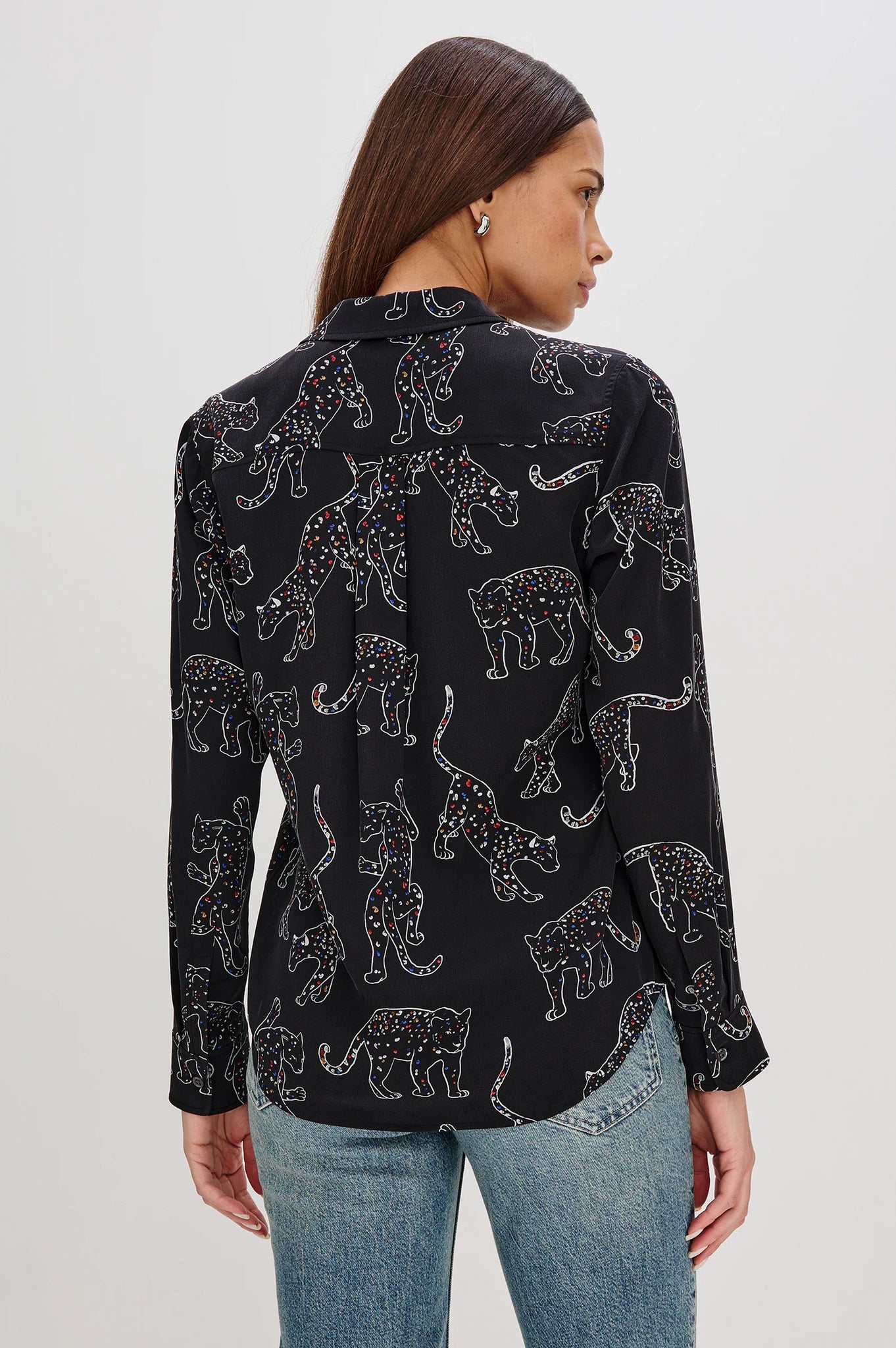 Woman wearing a black blouse with animal pattern and light blue jeans on a white background