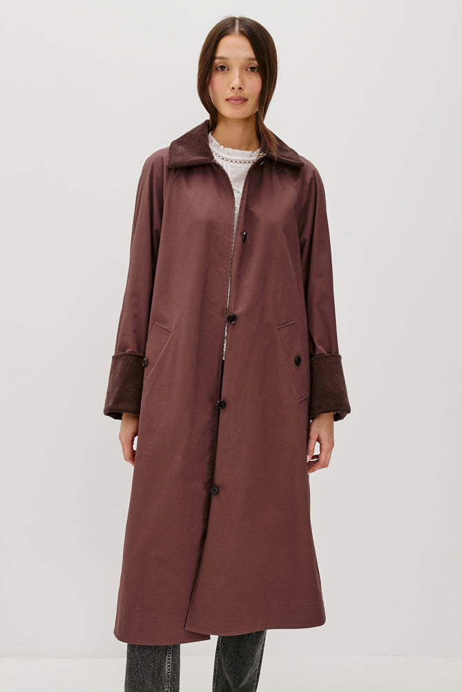 Woman wearing a long brown coat on a white background