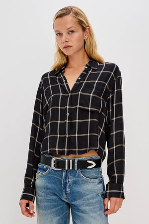 Woman wearing a black and white checkered shirt and blue jeans on a light gray background