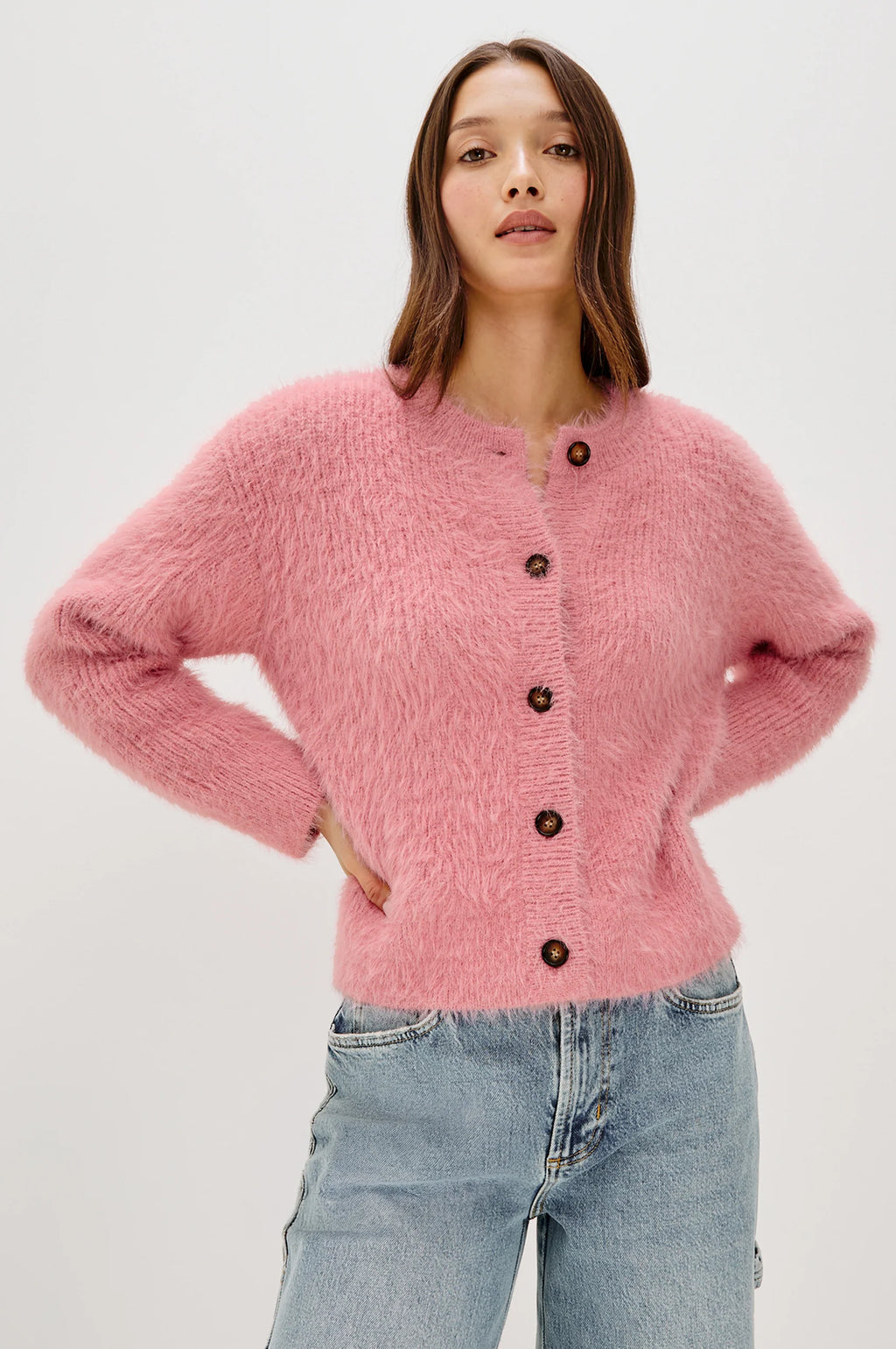 Woman wearing a pink cardigan with button details on a white background