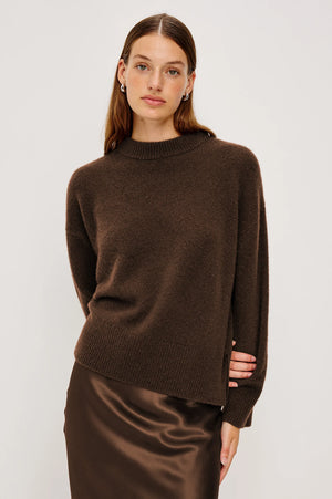 Woman wearing a brown sweater and skirt against a white background