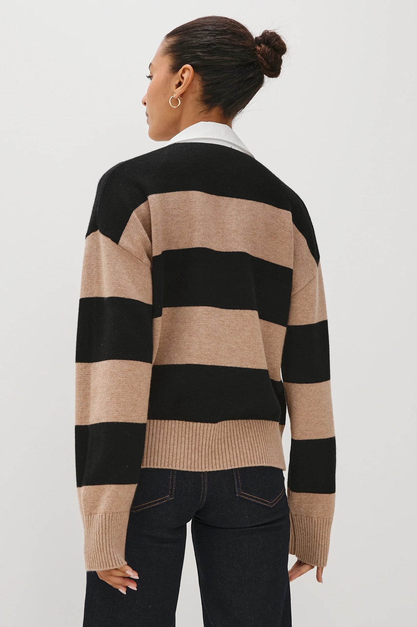 Person wearing a black and beige striped sweater on a white background