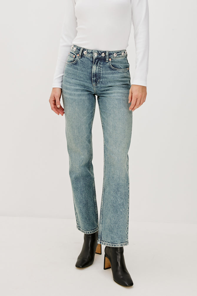 Person wearing light blue jeans and black boots on a white background