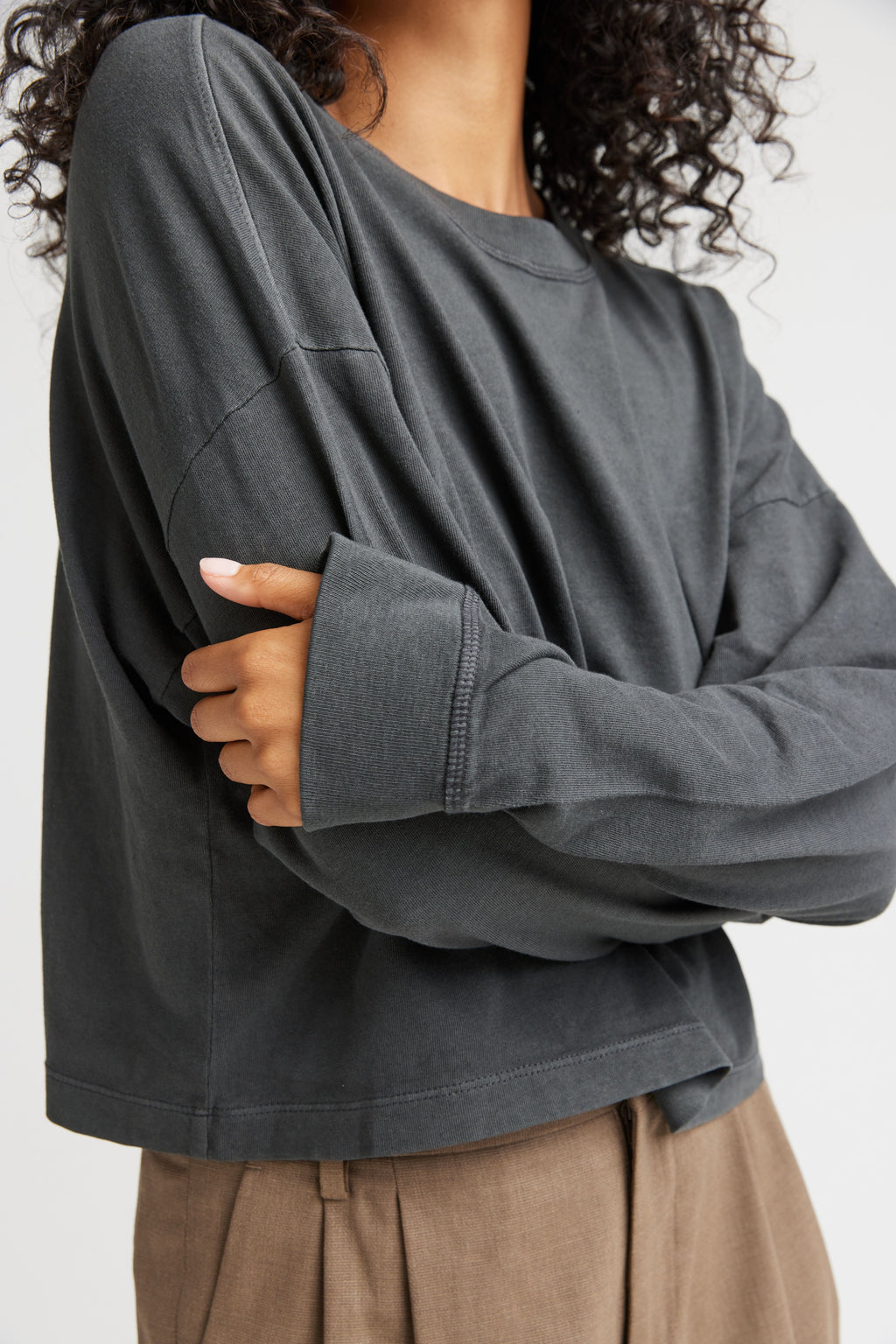 Person wearing a gray oversized sweatshirt with a neutral background