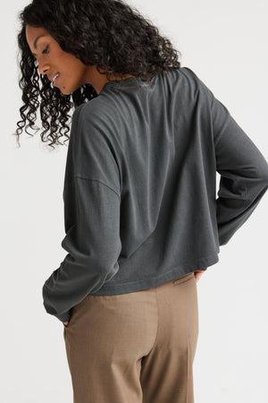 Woman wearing a gray long-sleeve top and beige pants on a white background