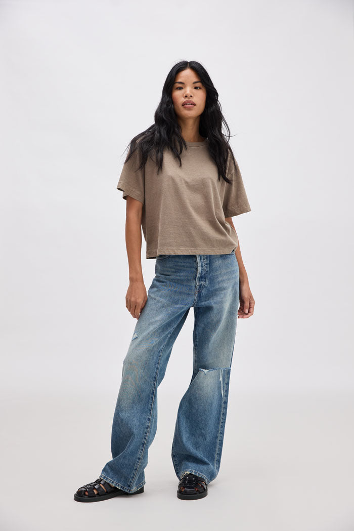 Woman wearing a brown t-shirt and blue jeans on a white background