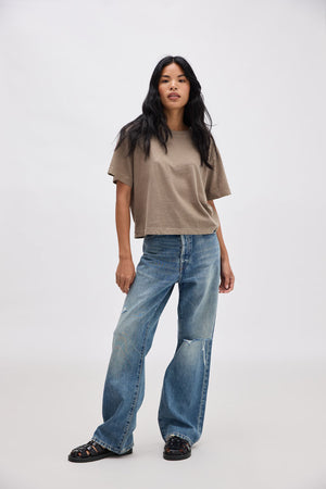 Woman wearing a brown t-shirt and blue jeans on a white background
