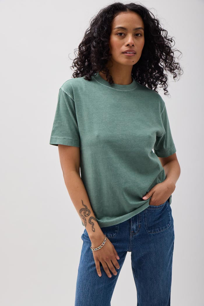 Woman wearing a green t-shirt and blue jeans against a white background