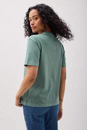 Person wearing a green t-shirt and blue pants against a white background