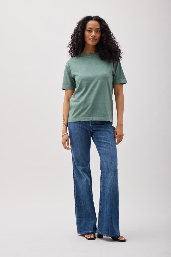 Woman wearing a green t-shirt and blue jeans on a white background