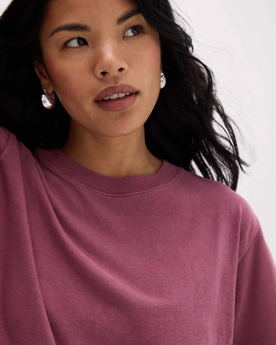 Woman wearing a mauve sweatshirt against a white background
