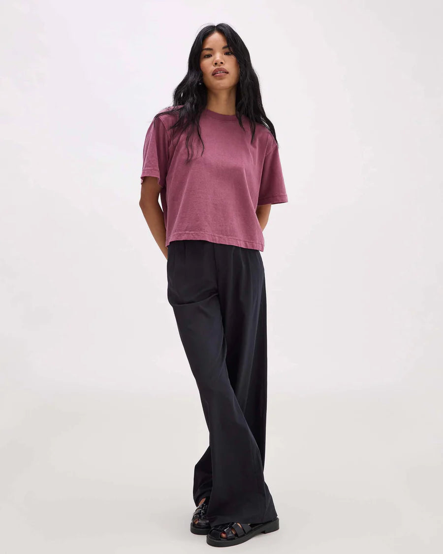 Woman wearing a mauve t-shirt and black pants on a white background