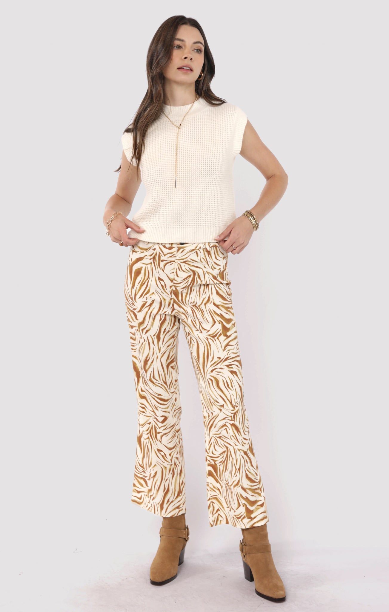 Woman wearing a sleeveless top and patterned pants on a white background