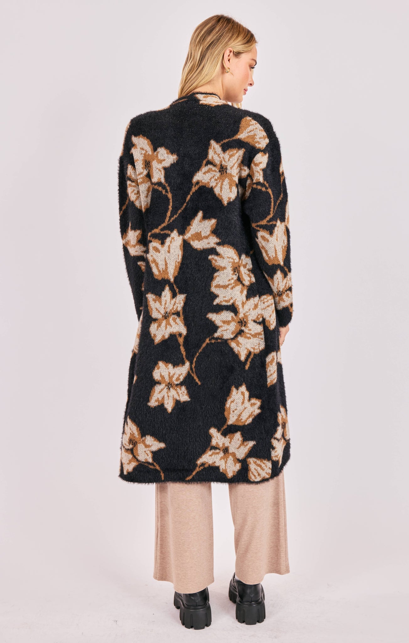 Woman wearing a black floral cardigan on a white background