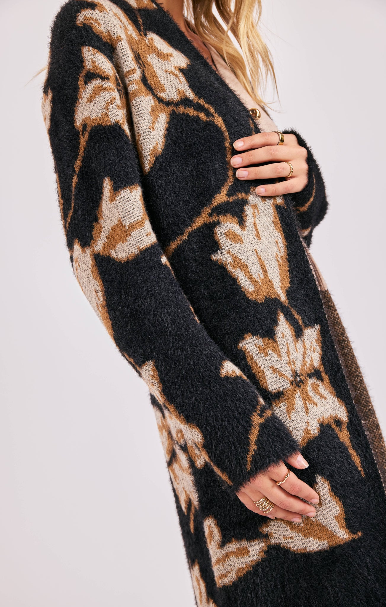 Black and brown patterned cardigan worn by a person on a white background