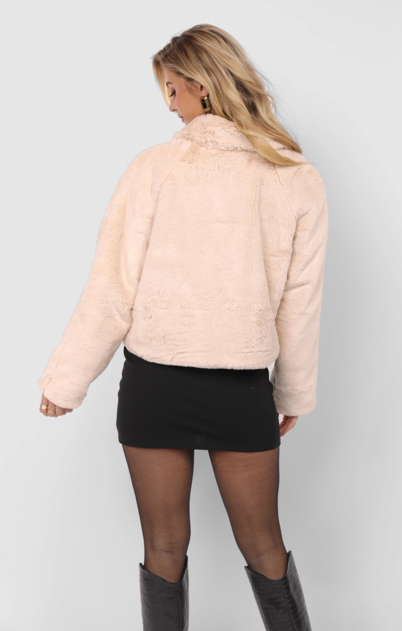 Woman wearing a light pink puffer jacket on a plain background