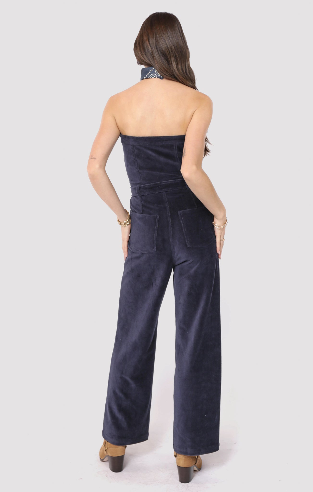 Woman wearing a strapless navy jumpsuit on a white background