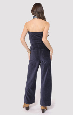 Woman wearing a strapless navy jumpsuit on a white background