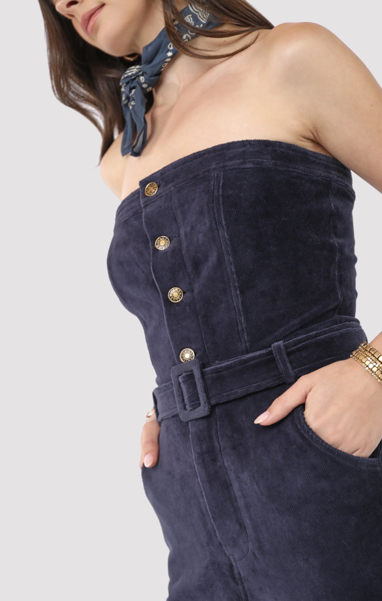 Navy strapless jumpsuit with gold buttons worn by a person on a white background