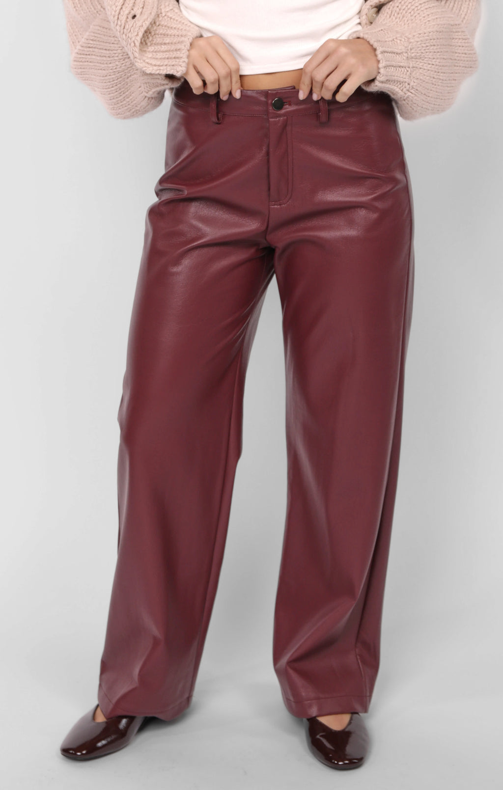 Maroon leather pants worn by a person on a white background