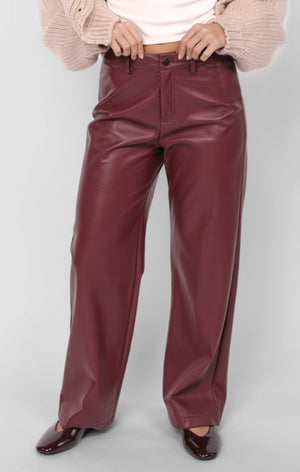 Maroon leather pants worn by a person on a white background
