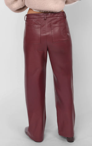 Maroon leather pants worn by a person on a light gray background