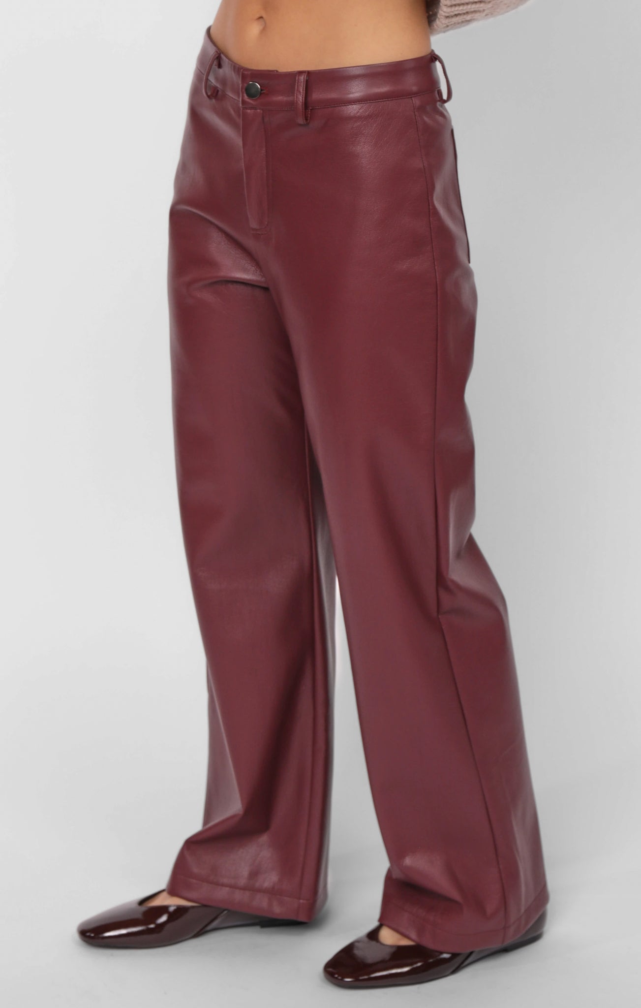 Maroon leather pants worn by a person on a white background