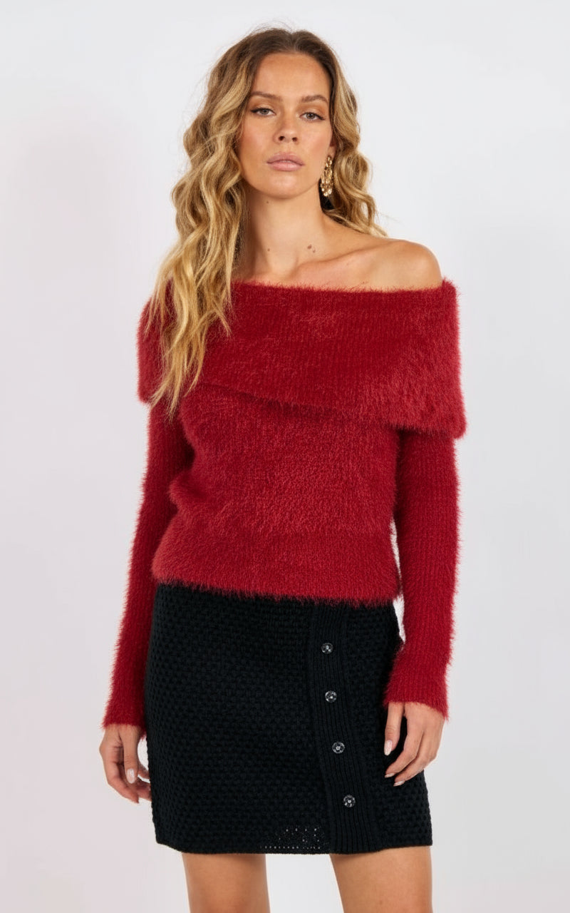 Woman wearing a red off-shoulder sweater and black skirt on a white background