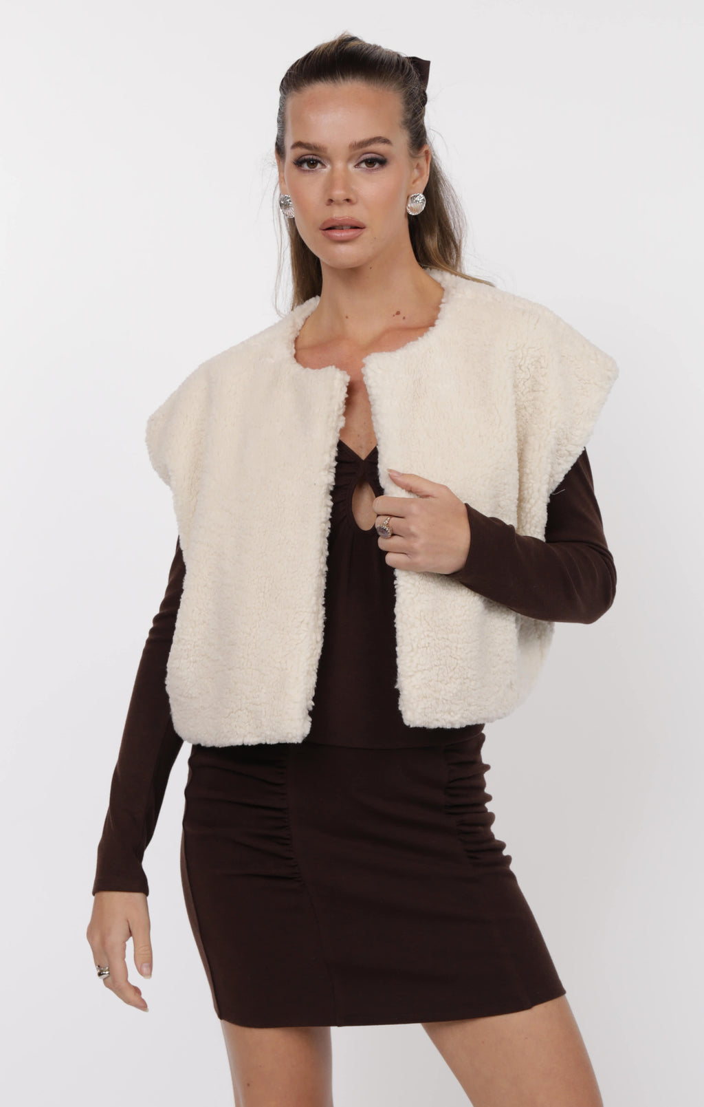 Woman wearing a white fur vest over a black dress on a white background