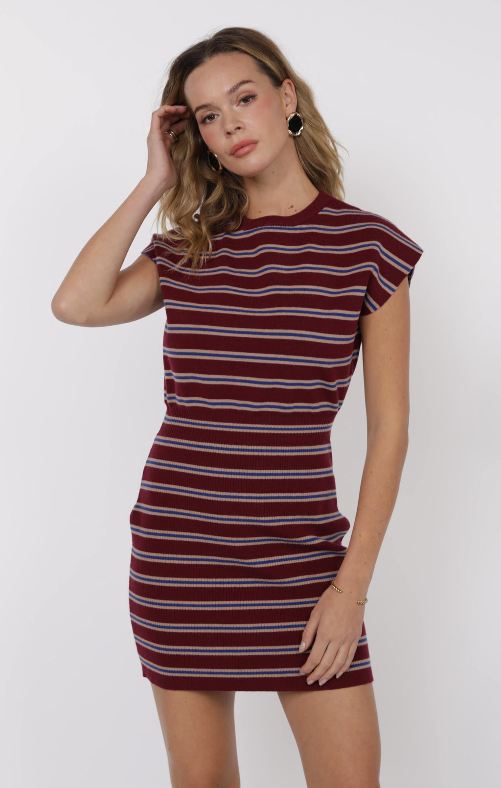 Woman wearing a maroon and white striped dress against a white background