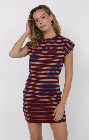 Woman wearing a maroon and white striped dress against a white background