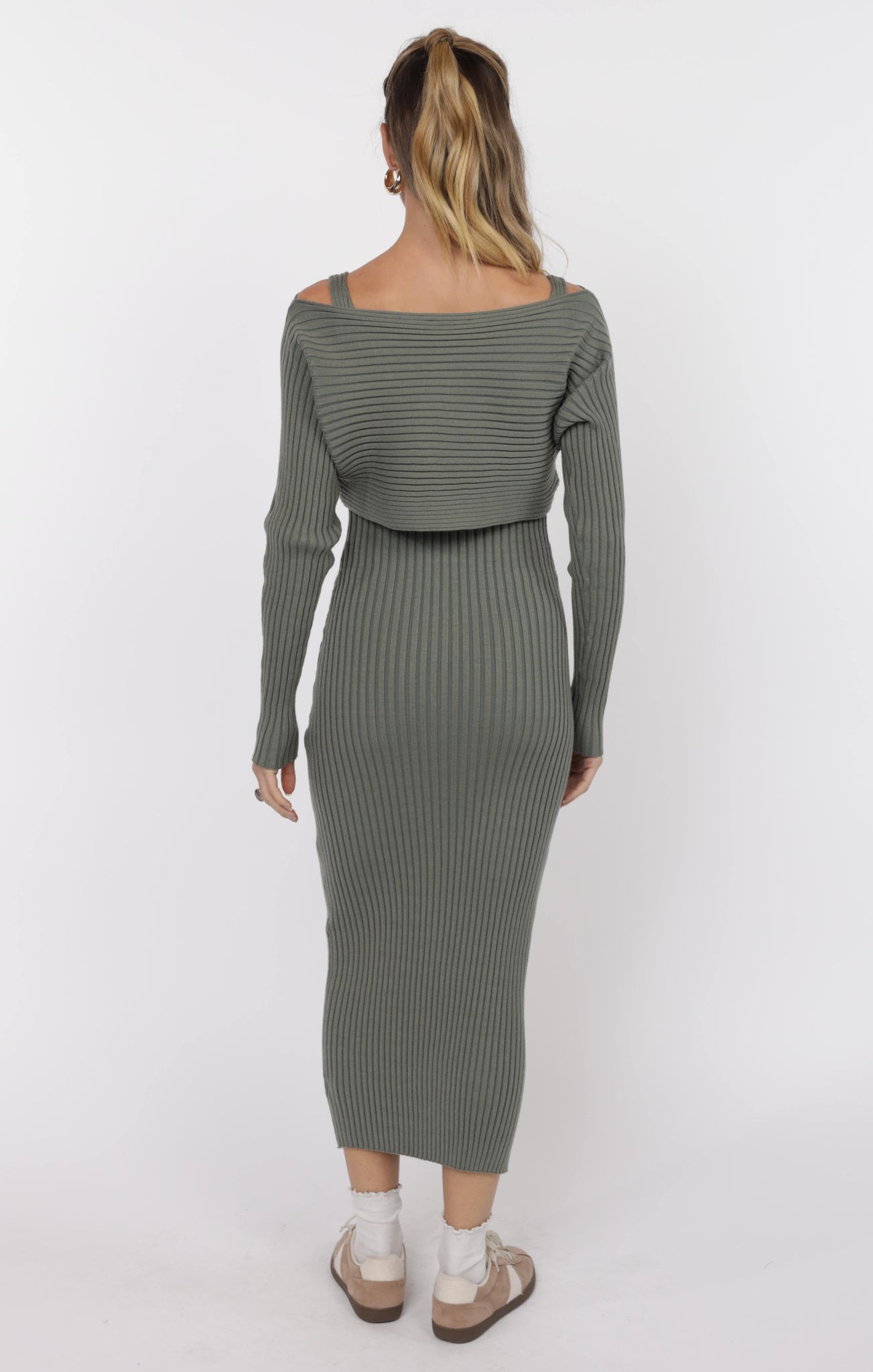 Woman wearing a green ribbed dress with a white background