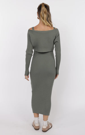 Woman wearing a green ribbed dress with a white background