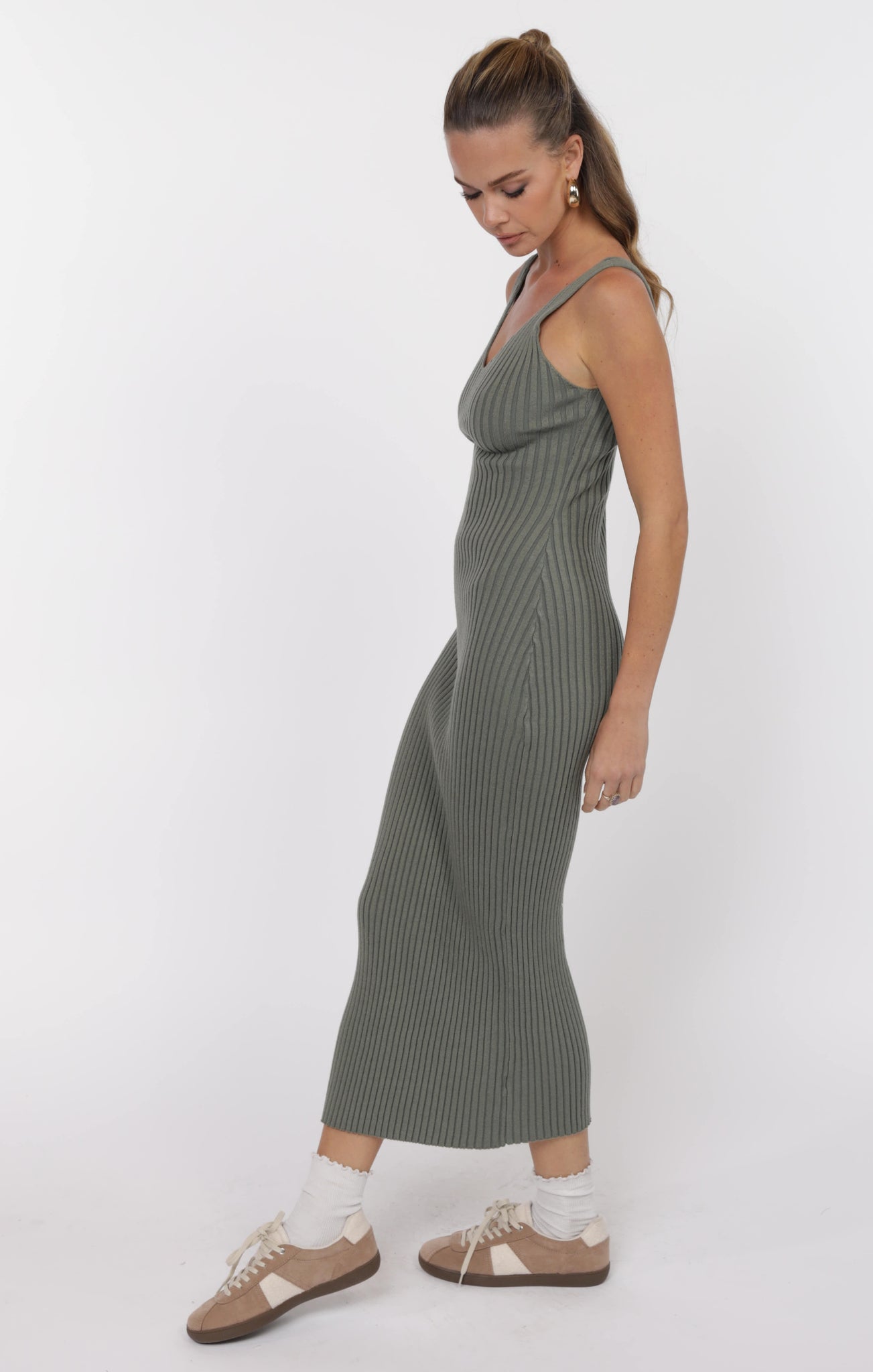 Woman wearing a green ribbed dress on a white background