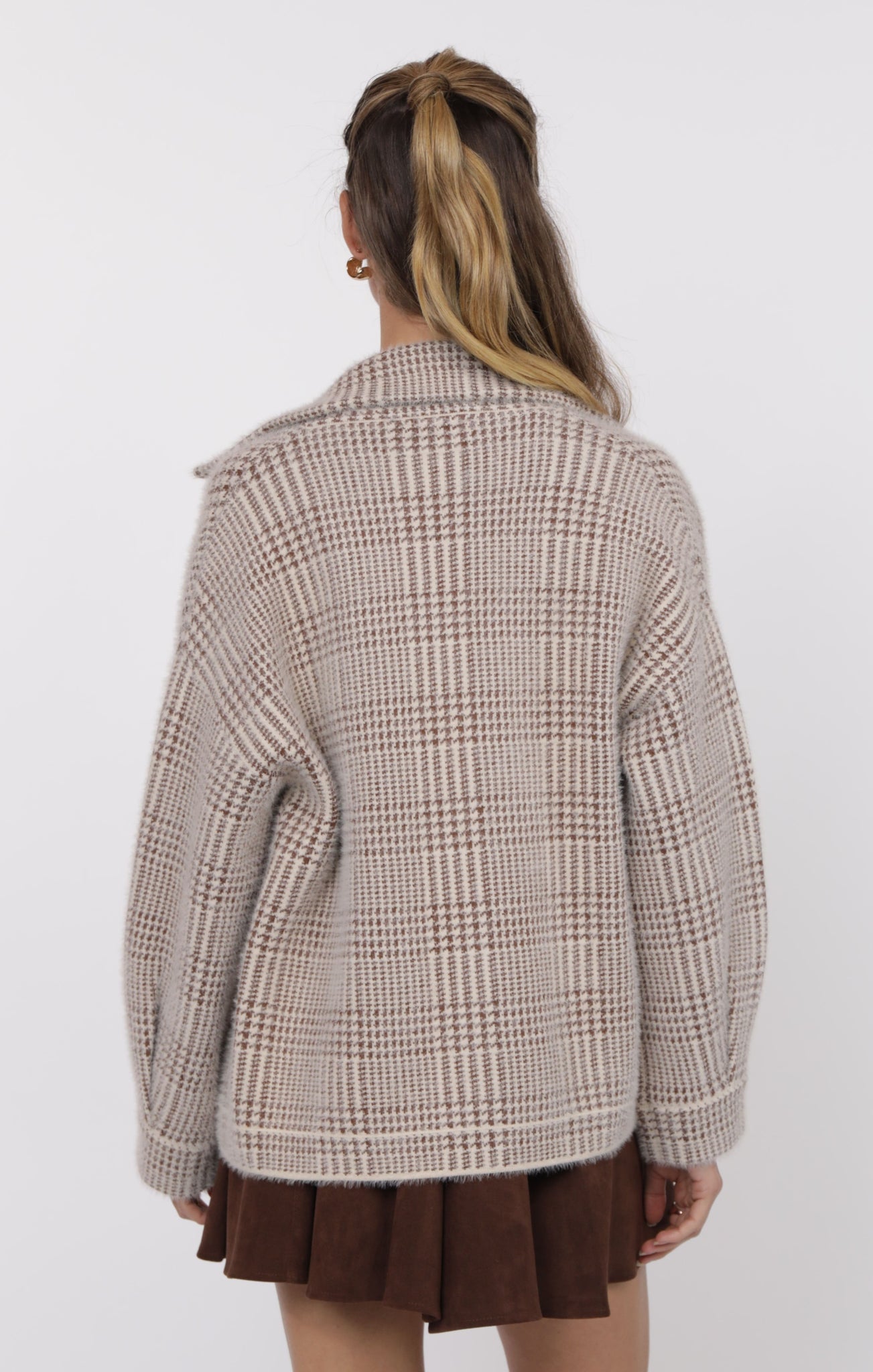 Person wearing a plaid jacket and brown skirt on a white background