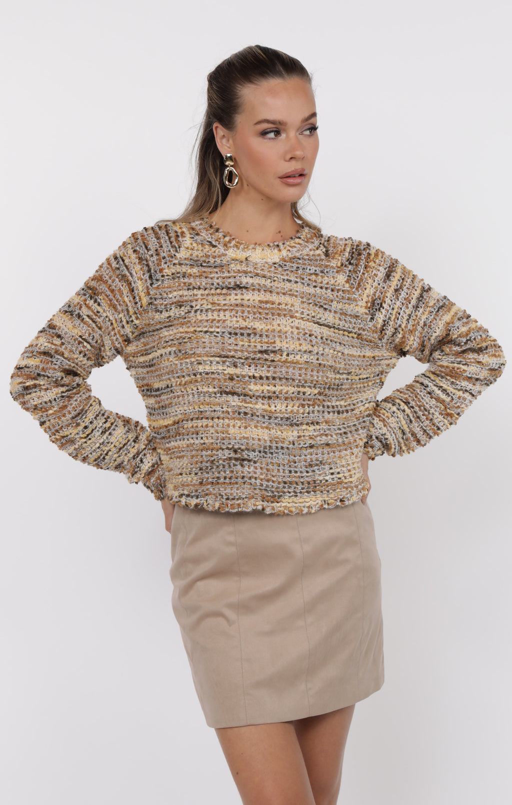 Woman wearing a textured sweater and beige skirt on a white background