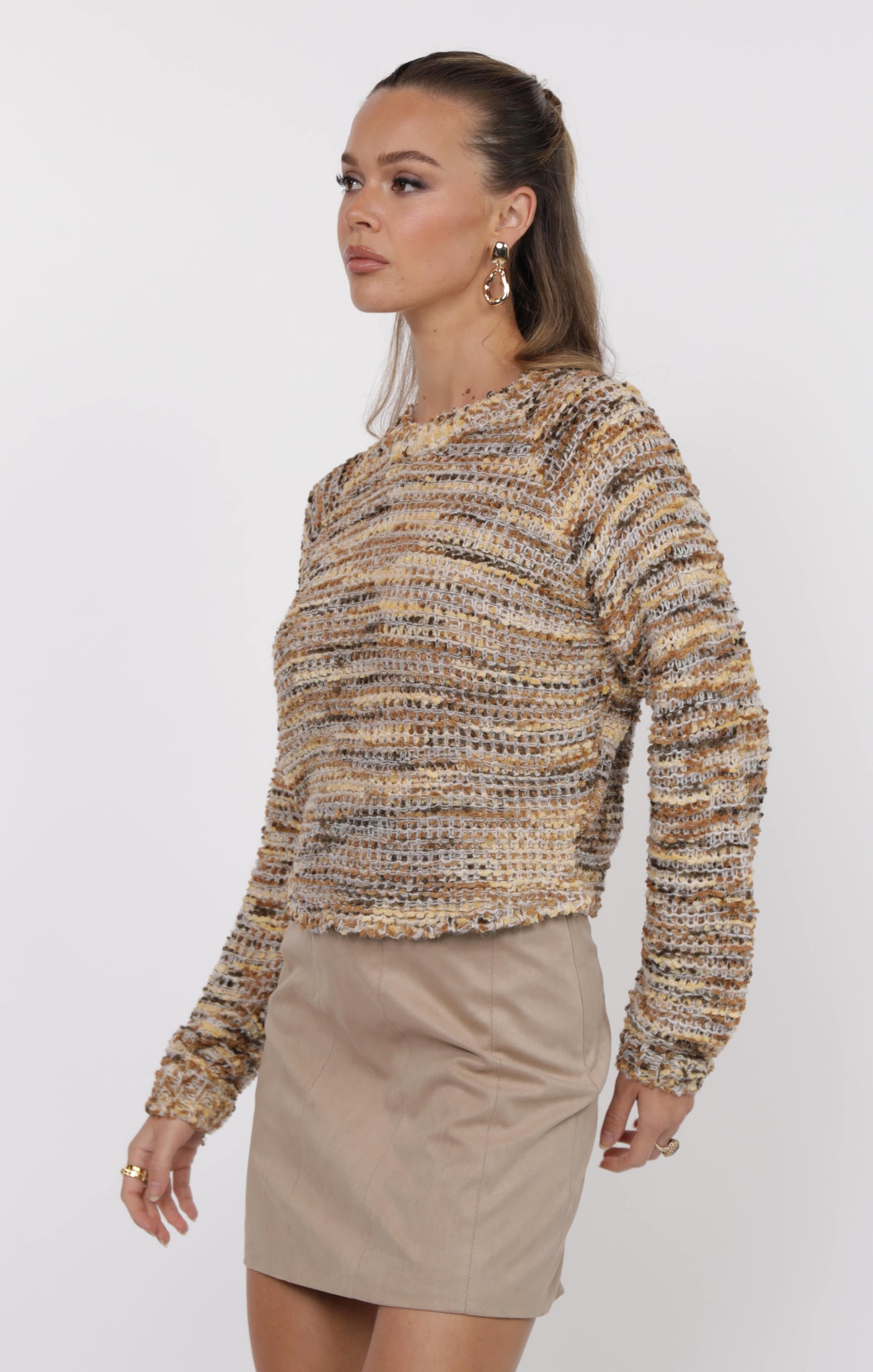 Woman wearing a patterned sweater and beige skirt on a white background