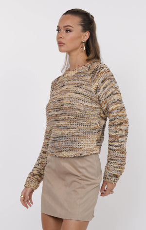 Woman wearing a patterned sweater and beige skirt on a white background