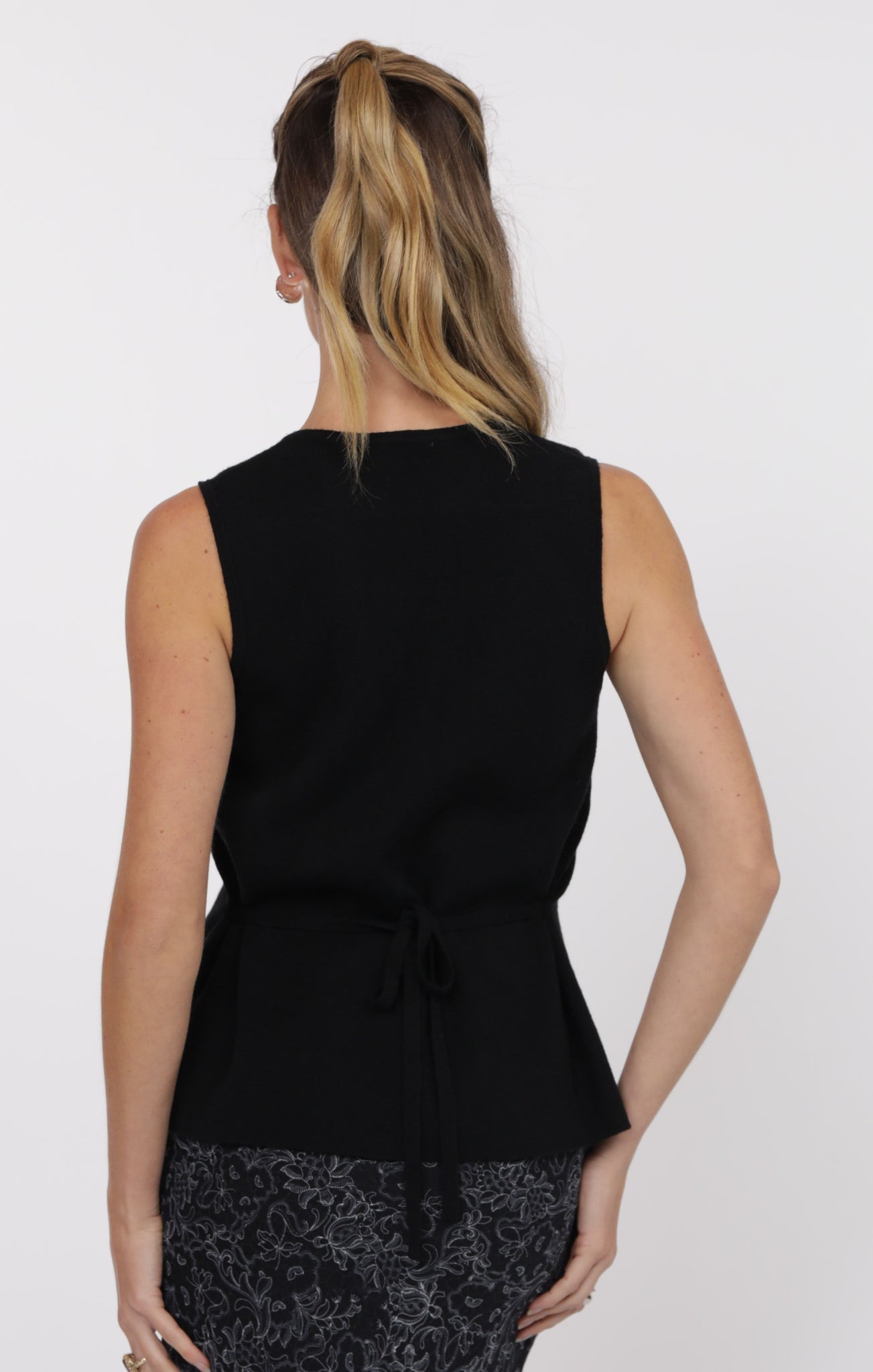 Woman wearing a black sleeveless top with a white background