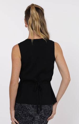 Woman wearing a black sleeveless top with a white background