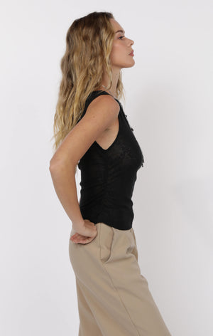 Woman wearing a black sleeveless top and beige pants on a white background