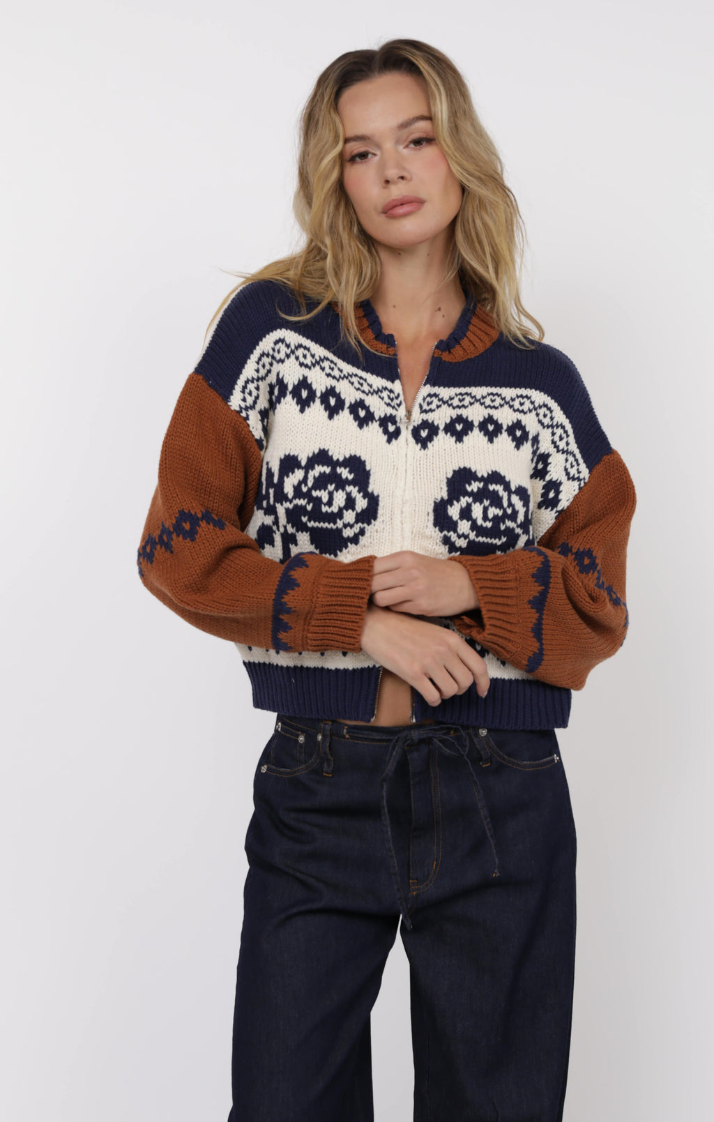 Woman wearing a patterned sweater with brown, blue, and white colors on a white background