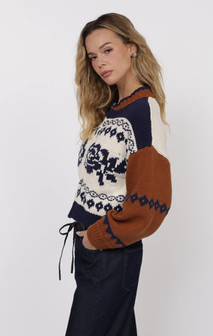 Woman wearing a patterned sweater with brown, white, and navy colors on a white background