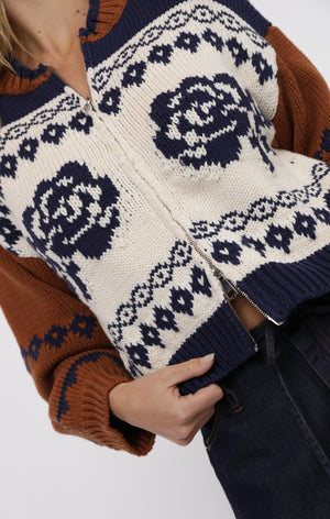 Close-up of a person wearing a sweater with a floral pattern on a white background