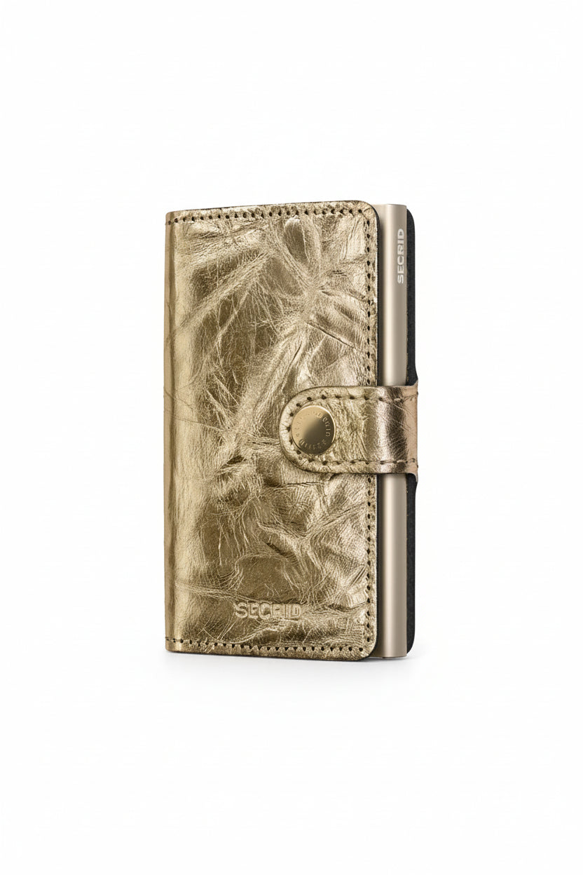 Metallic wallet with leaf pattern on a beige background