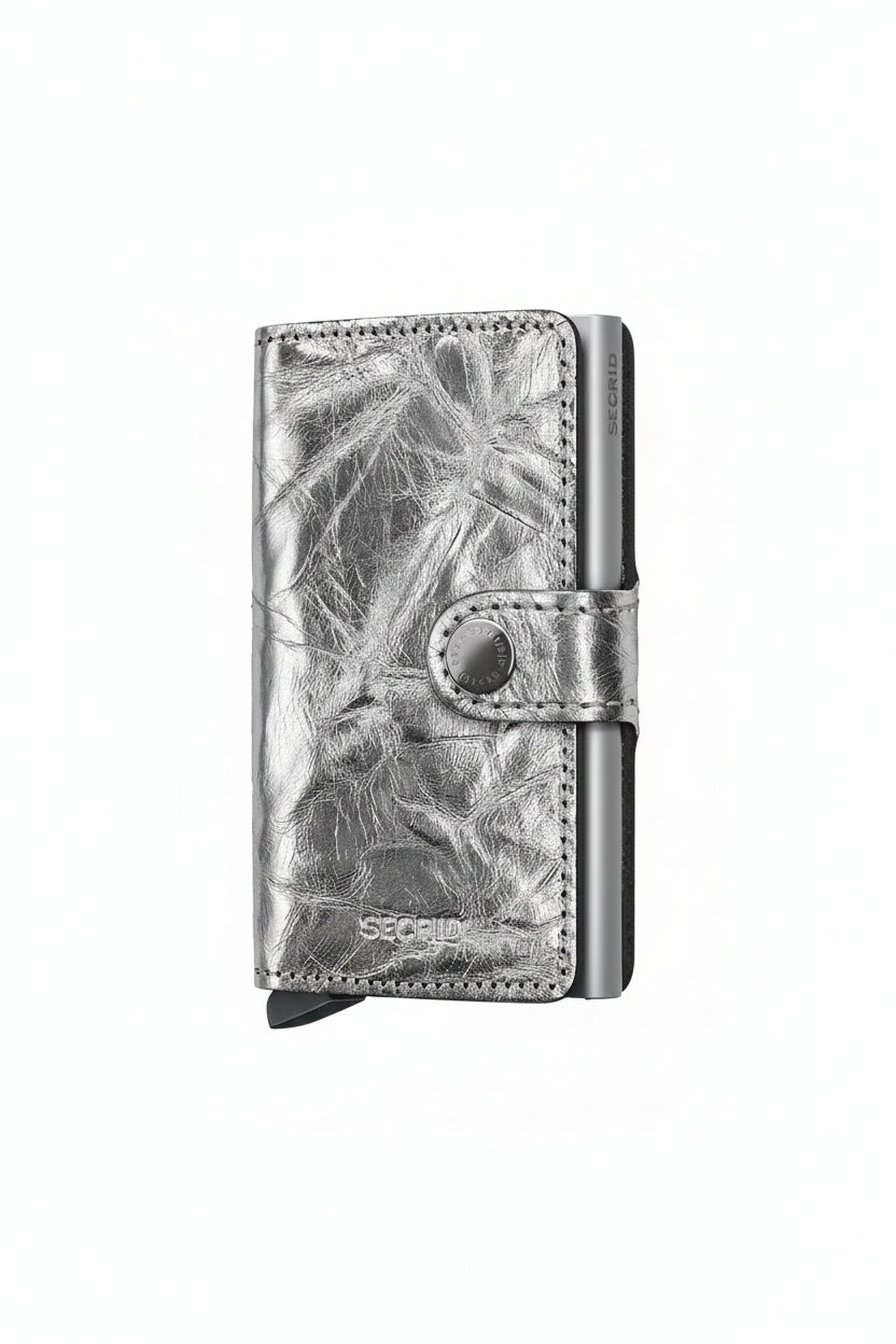 Silver wallet with leaf pattern on a beige background