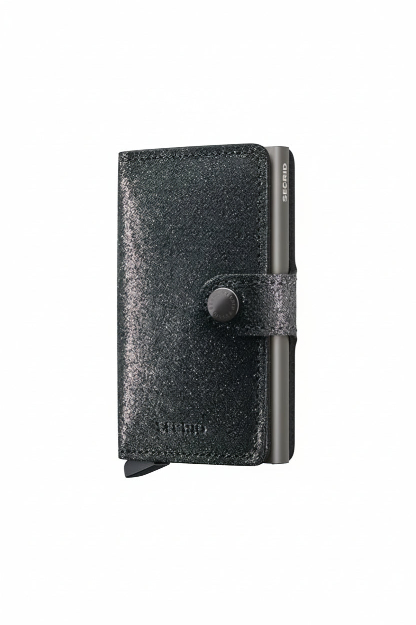 Black glittery wallet with a button on a beige background